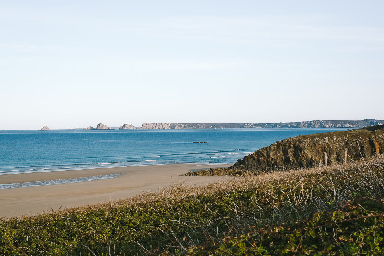 Beach scene with ocean and cliffs under a clear sky